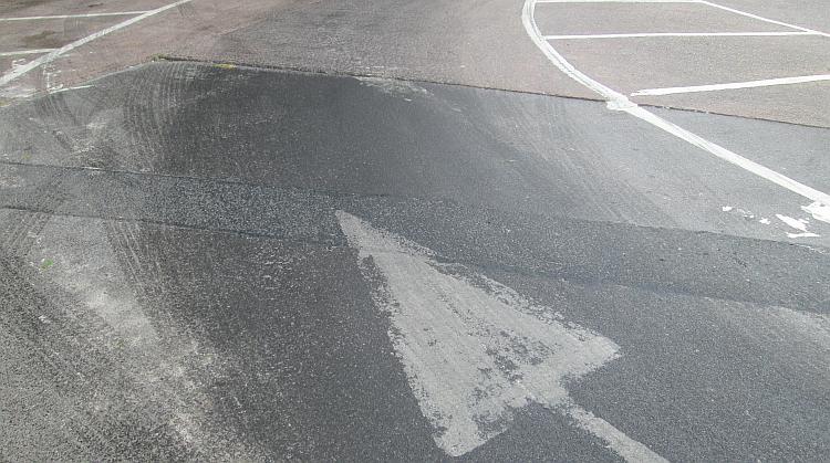 Dark, wet looking substance that's been spread by car tyres on the car park at Bridgewater Services