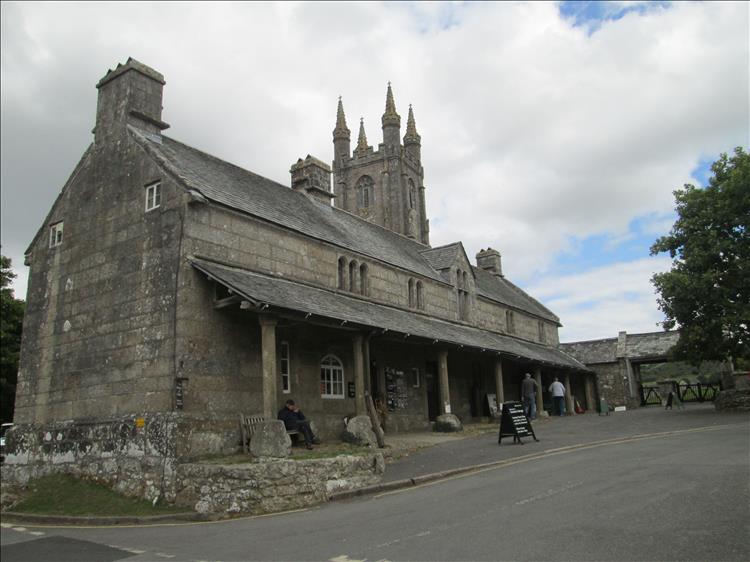 A large stone building with a information centre and Widecome in the Moor church behind it