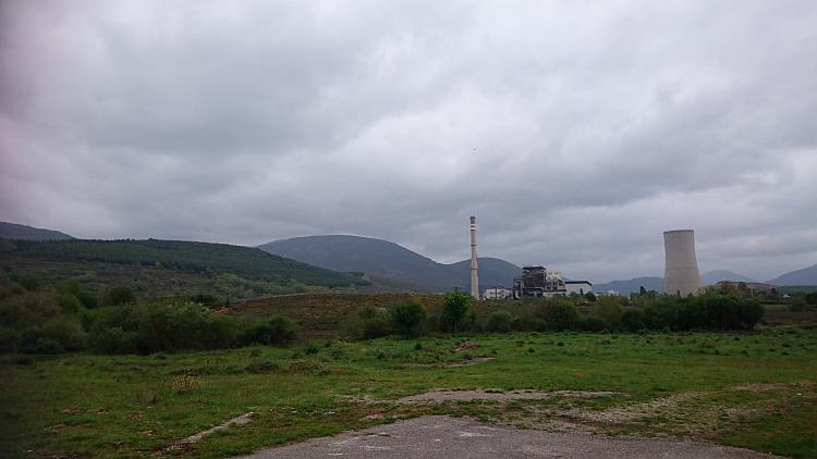 Big hills and green surrounding, among it all are the towers and massive building of a power station