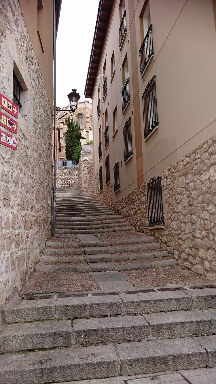 An old and worn stairway makes it's way up a narrow gap between buidlings in Burgos