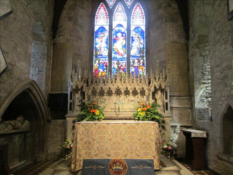 Inside the church alter has ornate carved stonework and detailed bright stained glass windows