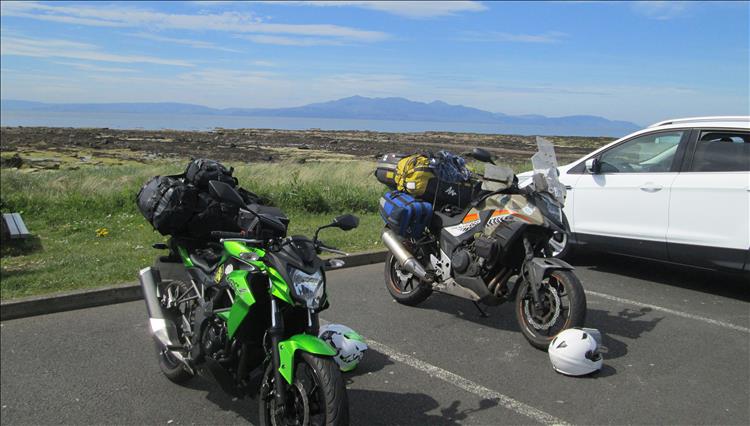2 motorcycles overladen with camping kit and the Isle of Arron in the misty distance