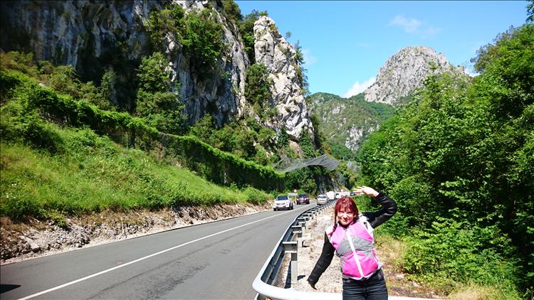 A deep gorge with steep white stone side, the road runs through it and Sharon is happy in th sun