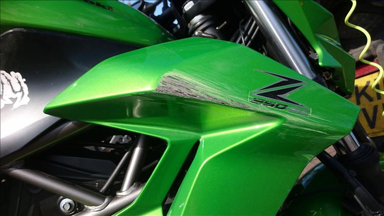The bright green side panel has deep scratches through the paint to the black plastic below