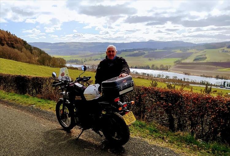 Steve stands by his Enfield against a beautiful rolling hills backdrop