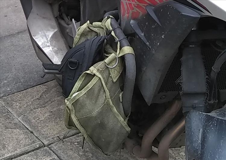 A dirty scruffy army surplus bag hangs from the crash bar of Ren's 500
