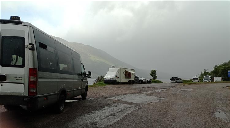 W can see hills, just about, in the mist and rain of a parking area with campers and cars