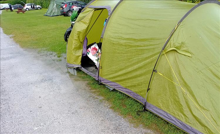 The left side of the tent is by the edge of the track and there's a puddle beside the tent