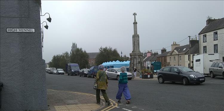 Wigtown market square with a cenotaph, market stalls, trees houses and cars