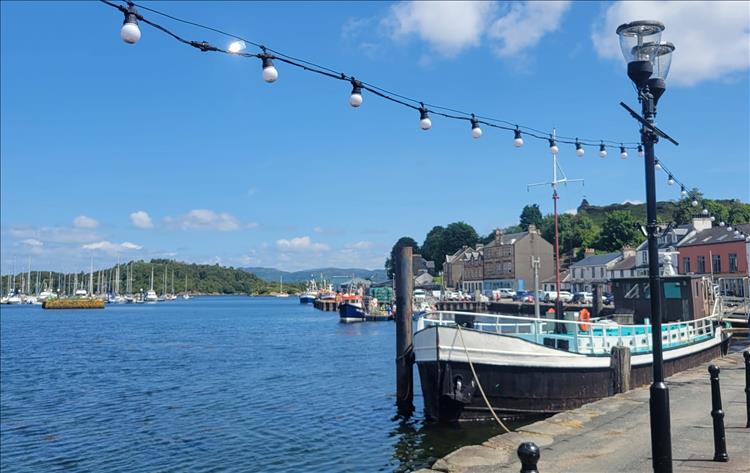 Clear blue skies, a fishing vessel in the harbour and the houses around the harbour