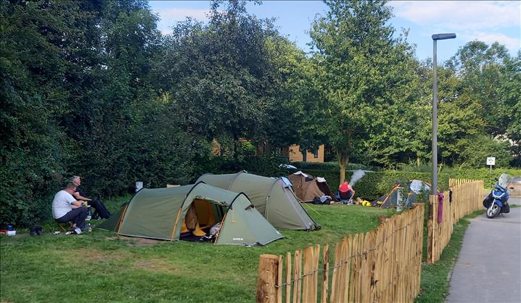 Tents with the small bikes in the distance and surrounded by trees