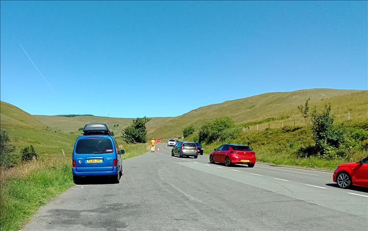 Blue skies, big hills, a layby and a man with a stop/go sign and a little traffic