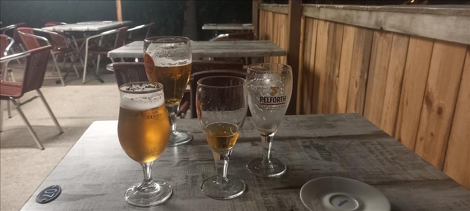A few half empty beer glasses on a table in a room filled with steel tubular chairs and modern tables