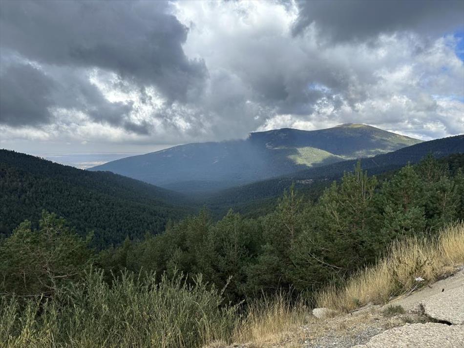 Heavy dark clouds begin to shroud a green hilltop