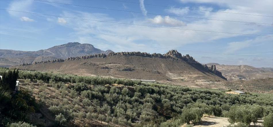 A curved hill has a crest of rocky outcrops that look like shark teeth