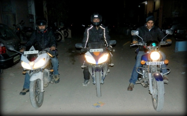 3 indian motorcyclists side by side riding through a dark street