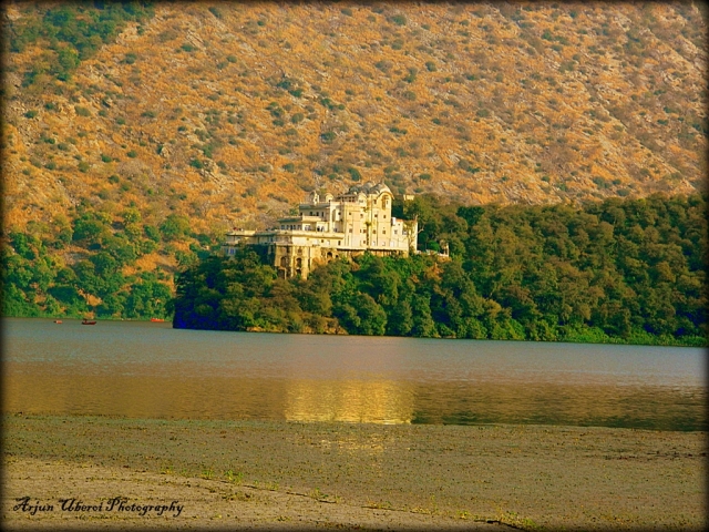 a white palace in trees at the edge of a lake