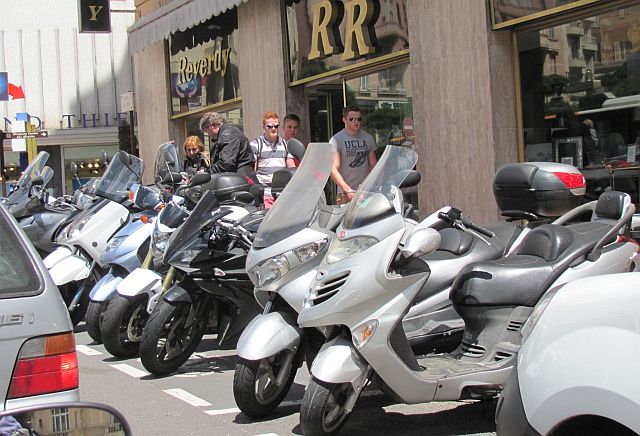 a line of scooters parked at the roadside in the cramped streets and traffic in monaco