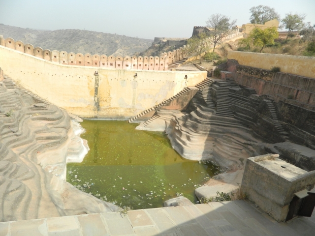 a pond in the base of sculptured steps and ridges in an indian palace