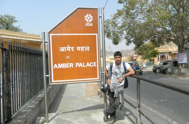 a motorcyclist posing by the amber palace sign
