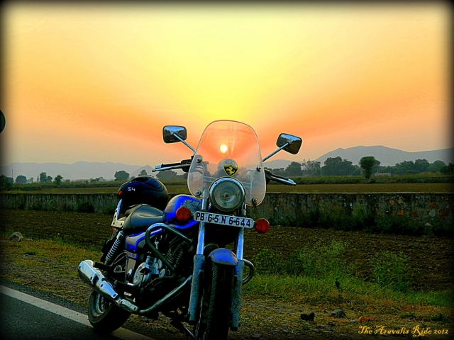 bajaj 220 motorcycle with roange sun seen through the wind screen