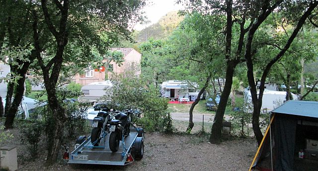 the campsite at la colle sur loup with trees on a steep hill and 2 bikes on a trailer