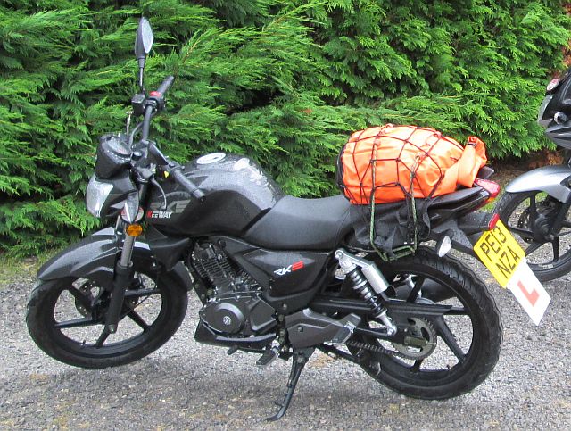 keeway rks 125 in black with a bright orange bag on the rear seat