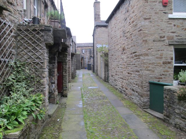 a terrace of stone built houses on a narrow cobbled path in hawes