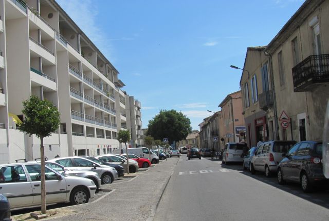 to the left of the street modern white apartment block, to the right old french terraces