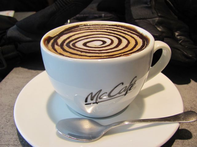 cup of cappuccino coffee with swirls of chocolate on the froth at the mcdonalds in bourg-en-bresse