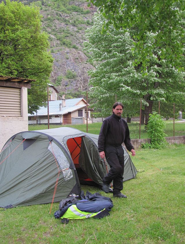 the bf coming out of the tent at the campsite in bourg d'oisans. rocky hillside behind
