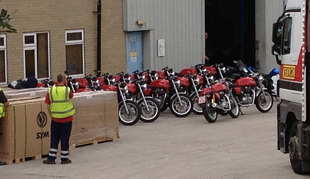 10 or 15 red royal enfield cafe racers outside a warehouse