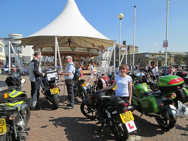 sharon stands next to her new 125 with l plates in the sunshine at the carousel at southport