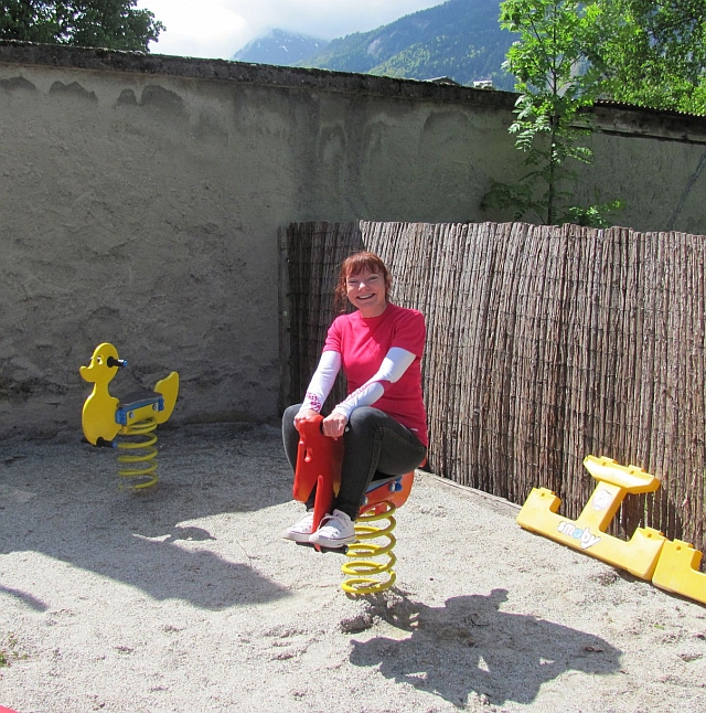 sharon on the spring mounted wooden horse smiling and beaming at la piscine campsite bourg d'oisans