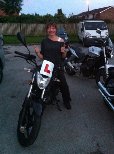 sharon gives us a big smile and thumbs up on her own bike in a car park
