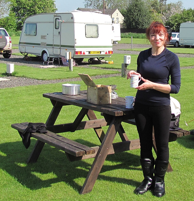Sharon with a cup of tea in the sun at the campsite in cambridge