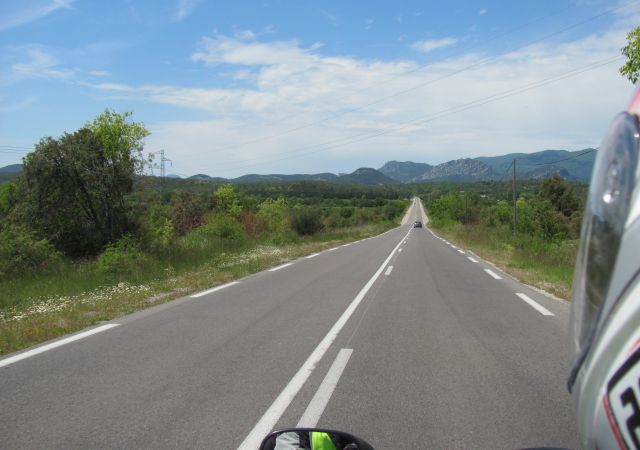 a long straight empty road vanishes into the distance in southern france's sunshine