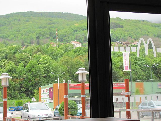 hills and greenery in the distance and retail estate in the foreground framed by the window of the mcdonalds in Bourg-en-Bresse