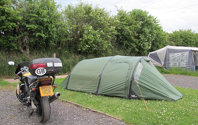 The tent and the motorcycle on the campsite at squires cafe showing the grass and gravel