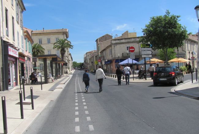 a busy broad french street with classic buildings either side in nimes