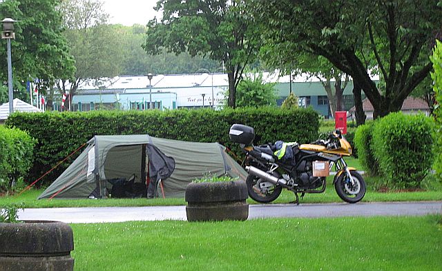 the tent and the bike at the campsite in epernay. Hedges, grass and surrounding buildings