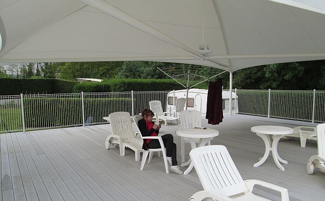 a large white canopy, deck chairs and tables, decking all at les rioms