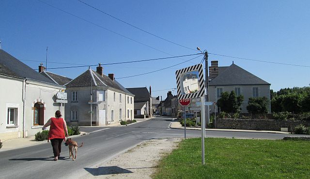 lady walking a dog in a french town in the sun