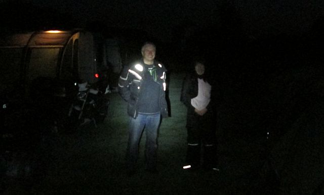 2 bikers in the pitch dark at the campsite, barely illuminated