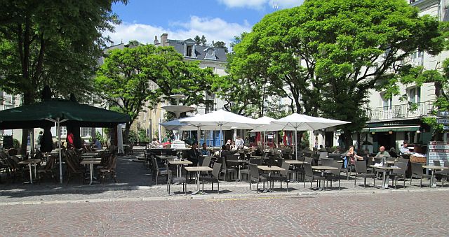 a broad town square filled with tables, chairs and canopies in chinon