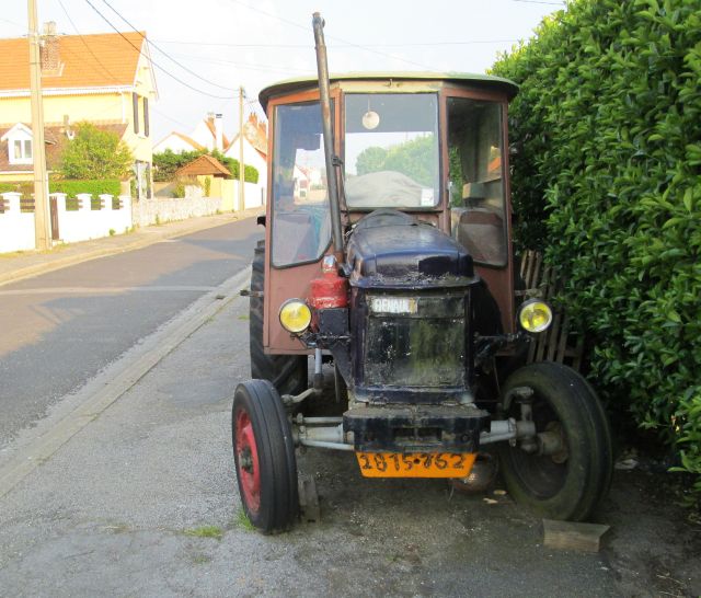 an old tractor in a poor state on the footpath of a french seaside town