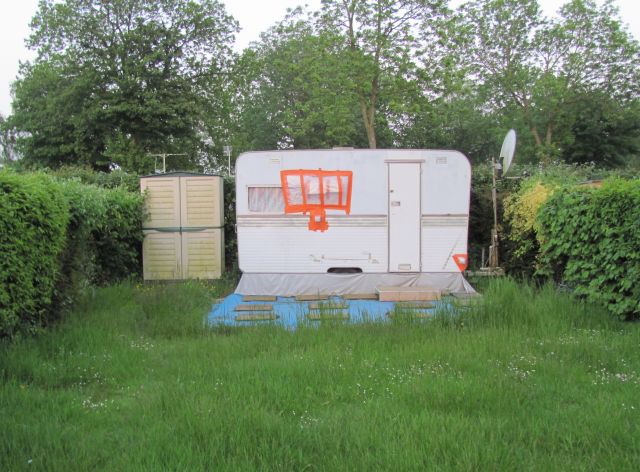 a small worn out caravan with patches in thick grass at the friaucourt camping municipal