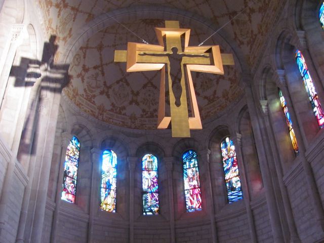 large gold coloured cross hanging from fine wires in the bastille, beautifully lit