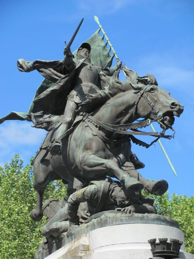 a massive bronze statue of joan of ark, on her horse mid battle