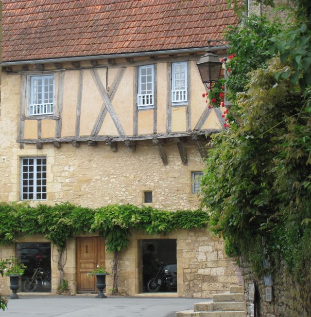 an ancient french house with a classic motorcycle in 2 windows ground floor